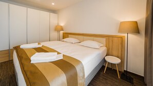 A hotel room with a bed, bedside lamps, a small table, and a wardrobe. - Apartment Dolfi (Senec)