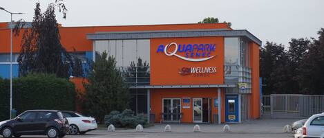 Un edificio con fachada naranja y un letrero que dice 'Aquapark Senec Wellness'.