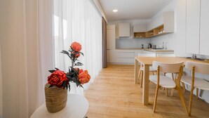 A modern kitchen with white cabinets, a wooden dining table, and chairs. - Apartment Dolfi (Senec)