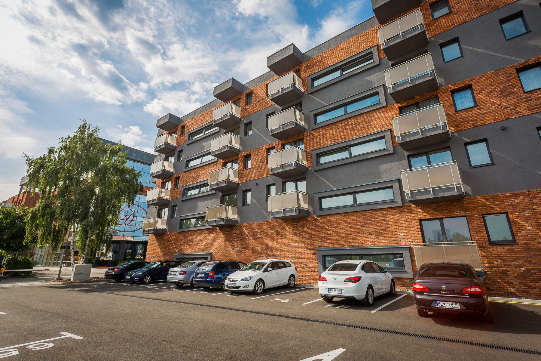 A multi-story residential building with a parking lot in front.