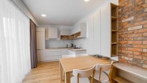 A modern kitchen with white cabinets, a wooden countertop, and a brick accent wall. - Apartment Dolfi (Senec)