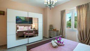 Ein Schlafzimmer mit Bett, Schminktisch, Spiegel, Stuhl und einem Fenster mit Vorhängen.