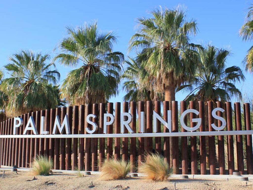 A wooden fence with the words "PALM SPRINGS" in white letters.