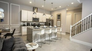 A modern kitchen with white cabinets, stainless steel appliances, and a central island with bar stools.