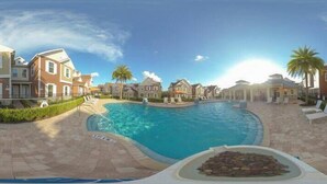 A swimming pool surrounded by brick houses with a clear sky.