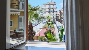 A balcony with a view of a street, palm trees, and buildings.