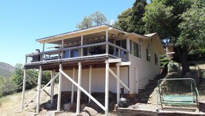 A two-story house with a balcony, a satellite dish, and a stone foundation.