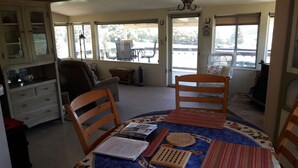 A room with a dining table, two chairs, a cabinet, and a large window.