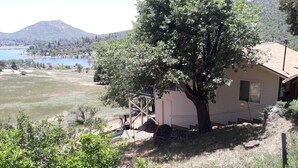 A small house with a tree in front, a clear view of a lake, and a mountain in the background.