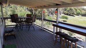 A covered outdoor area with a wooden deck, a table with chairs, and a bench.