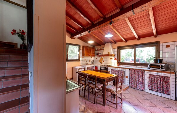 A kitchen with a wooden table and chairs, a stove, and a microwave. - Amazing home in Sassetta with WiFi (Sassetta)