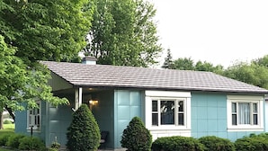 A single-story house with a sloped roof, a front porch, and a small front yard with trimmed bushes. - Blue Steel Lustron - Rare - Near Starved Rock Country (Grand Ridge)