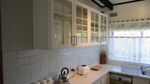 A kitchen with white cabinets, a toaster, a kettle, and a dishwasher. - Honeysuckle Beach Cottage - Silverleaves (SILVERLEAVES)