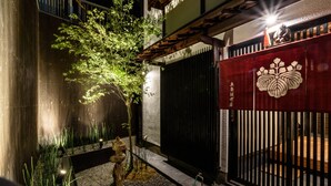 A traditional Japanese-style building with a wooden exterior, a black gate, and a red decorative panel with a white emblem. - Gojozaka Samurai Machiya, Gojozaka Samurai Machiya (Kyoto)