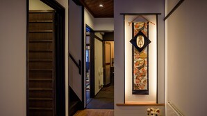 A hallway with a wooden floor, a dog statue, and a hanging decorative item. - Gojozaka Samurai Machiya, Gojozaka Samurai Machiya (Kyoto)