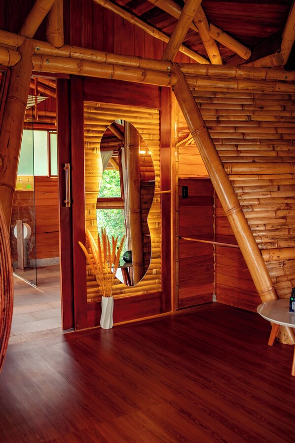 A wooden interior with a large mirror, a wooden floor, and a small table.