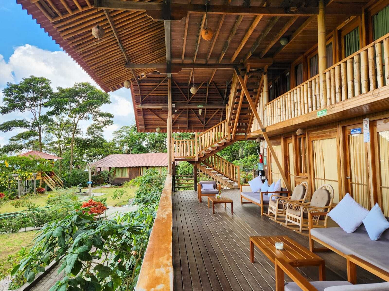 A wooden deck with outdoor seating, a staircase, and a view of the surrounding garden.
