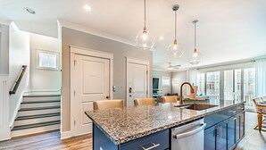 A modern kitchen with granite countertops, stainless steel appliances, and pendant lighting.