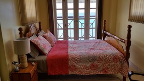 A bedroom with a bed, a bedside lamp, a nightstand, and a view of the sea through large windows. - Beachfront - Relaxing views (Speightstown)