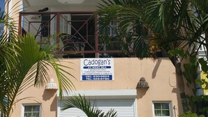A two-story building with a sign advertising 'Cadogan's at West Sea' as a fully furnished town house with 2 bedrooms, air conditioning, and cable TV. - Beachfront - Relaxing views (Speightstown)