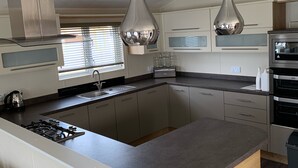 A modern kitchen with a central island, stainless steel appliances, and pendant lighting. - Beautiful Lakeside lodge with Hot Tub (LINCON)