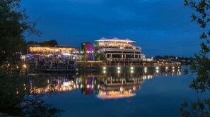 Un ristorante sul lungomare con posti a sedere all'aperto e un riflesso nell'acqua.
