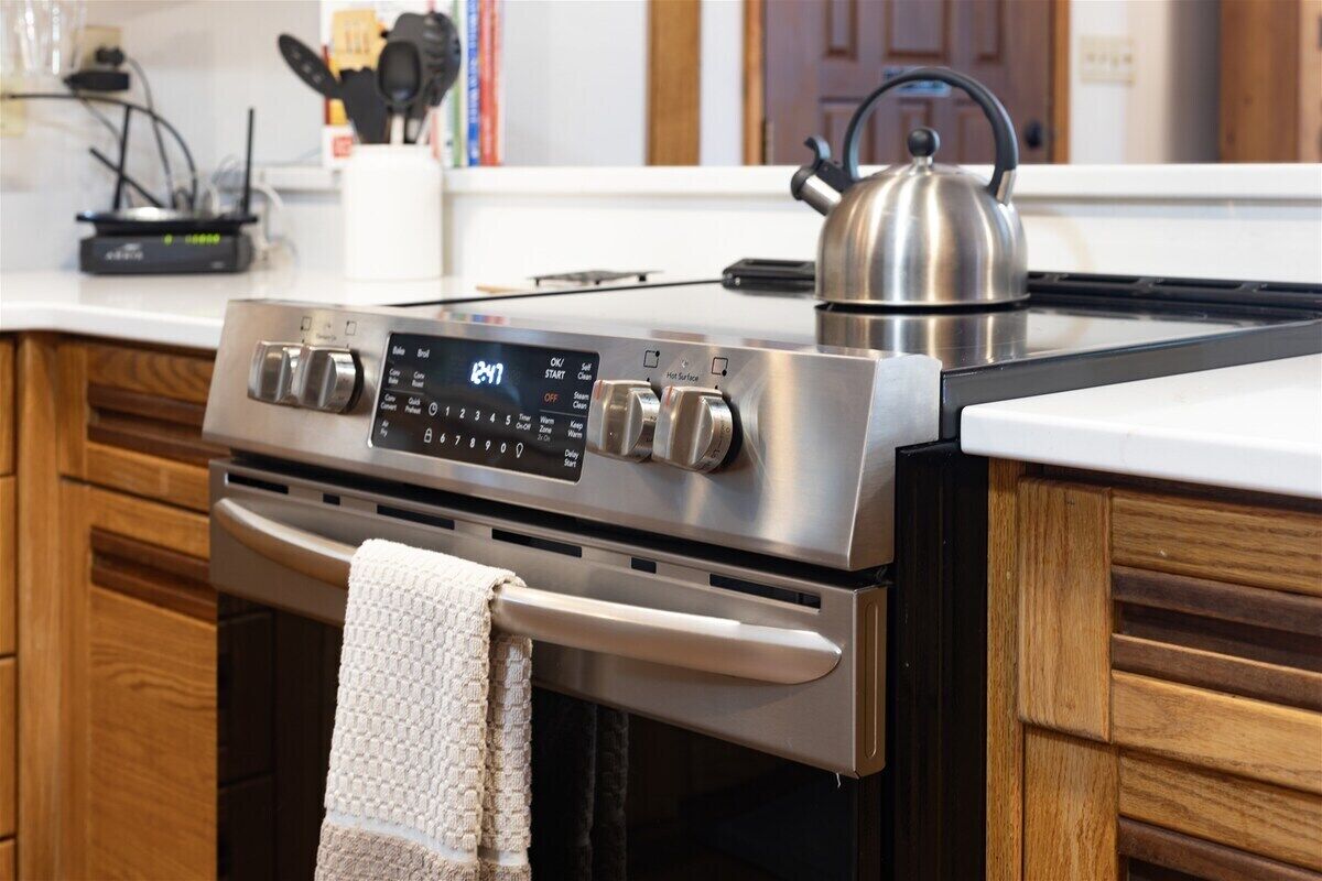 Una cocina moderna con estufa de acero inoxidable, panel de control digital y armarios de madera.
