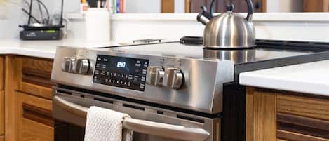Una cocina moderna con estufa de acero inoxidable, panel de control digital y armarios de madera.