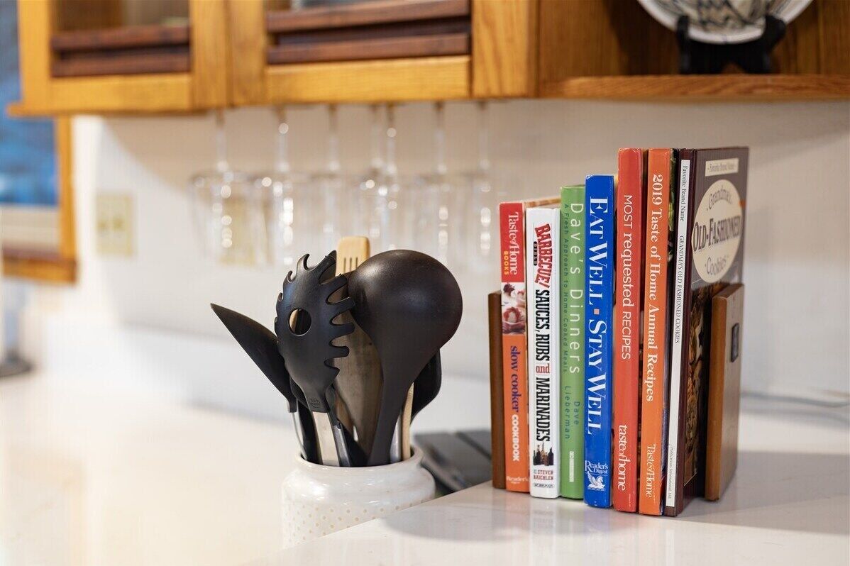 A kitchen counter with a collection of cookbooks and a utensil holder.