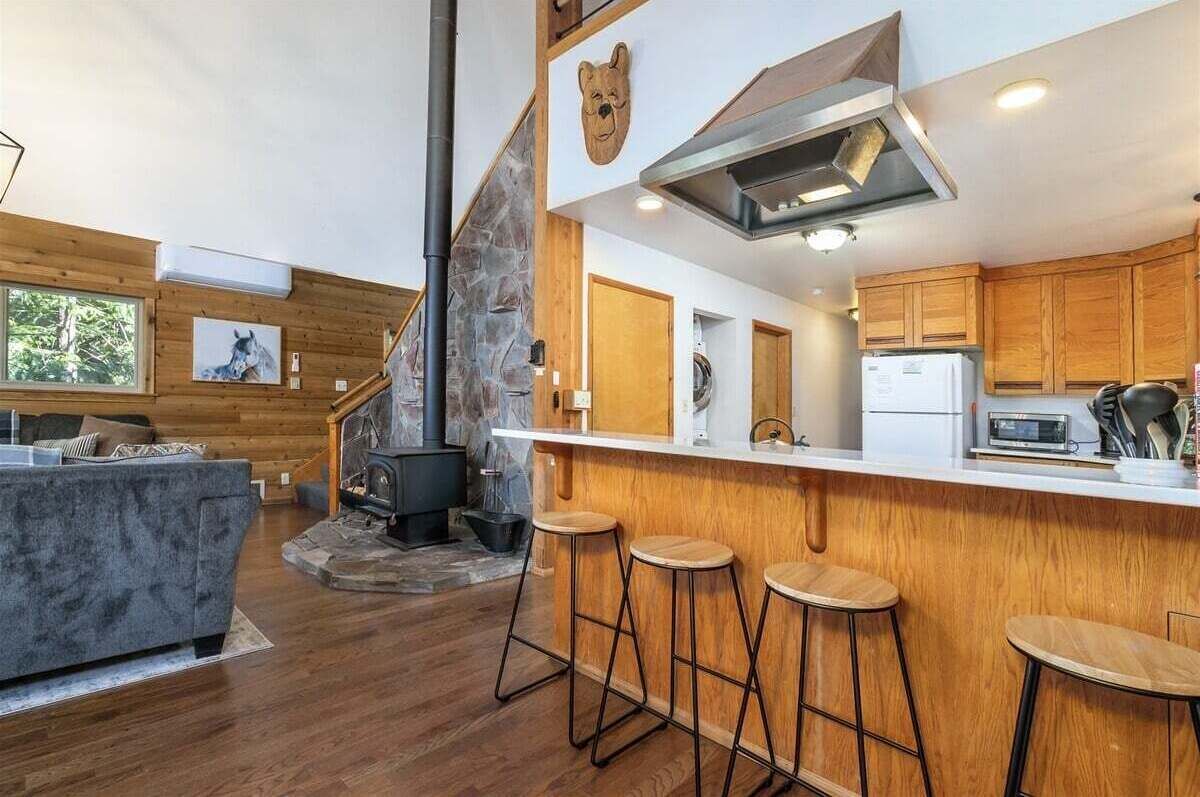Eine moderne Küche mit Kamin aus Stein, Holzbarhocker und einer großen Kochinsel.