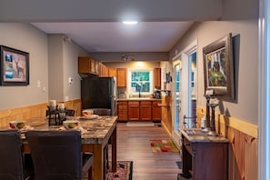 Una cocina compacta con armarios de madera, un comedor con mesa y sillas, y un ventanal que proporciona luz natural.
