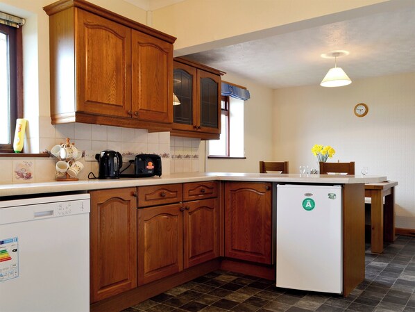 A kitchen with wooden cabinets, a white refrigerator, a coffee maker, and a dining table with chairs.