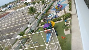 Una cancha de baloncesto con red, un parque infantil con toboganes y una zona de piscina con toboganes de agua.