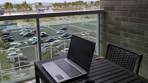 Un balcón con una laptop sobre una mesa, una silla y una taza.