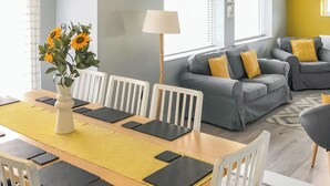 A dining area with a wooden table, white chairs, and a vase of sunflowers. - 4 bedroom accommodation in Criccieth, near Porthmadog (Criccieth, near Porthmadog)