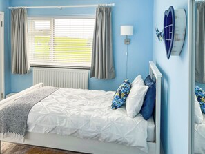 A bedroom with a bed, curtains, a wall-mounted lamp, and a window with blinds. - 4 bedroom accommodation in Criccieth, near Porthmadog (Criccieth, near Porthmadog)