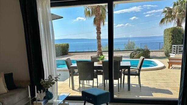 A modern living room with a large sliding glass door leading to a pool area. - Luxury villa Glory Palm in Makarska, private pool (Makarska)