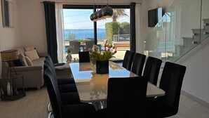 A modern dining area with a glass table and chairs, a sofa, and a view of the outdoors. - Luxury villa Glory Palm in Makarska, private pool (Makarska)