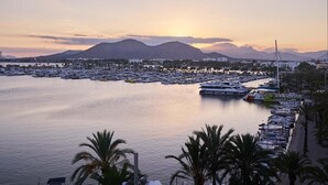A marina with boats docked, a waterfront promenade, and mountains in the background. - Luxury apartment on the top floor with sea view (Puerto Alcudia)