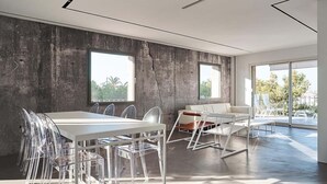 A modern interior with a concrete wall, large windows, a white table with transparent chairs, and a white sofa. - Luxury apartment on the top floor with sea view (Puerto Alcudia)