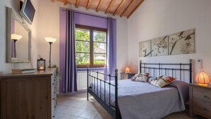 A bedroom with a bed, a dresser, a window with purple curtains, a radiator, and wall art. - Cozy home in Cecina Marina with WiFi (Cecina Marina)