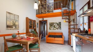 A compact kitchen with a dining area, a sofa, and a staircase leading to an upper level. - Cozy home in Cecina Marina with WiFi (Cecina Marina)