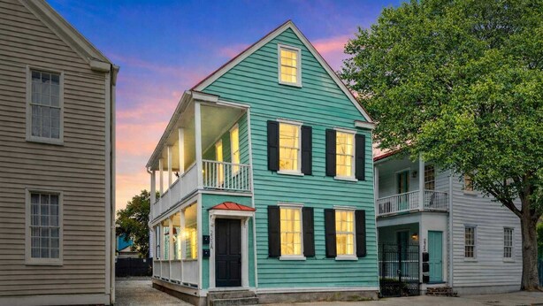 A two-story house with a balcony and a porch, featuring a traditional architectural style. - Spacious, Historic Home with Porches (Charleston)