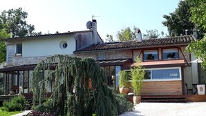 A two-story house with a tiled roof, a large garden with various plants, and a paved driveway.