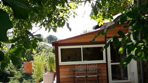 A wooden deck with a bench and a table, a window, and a door.