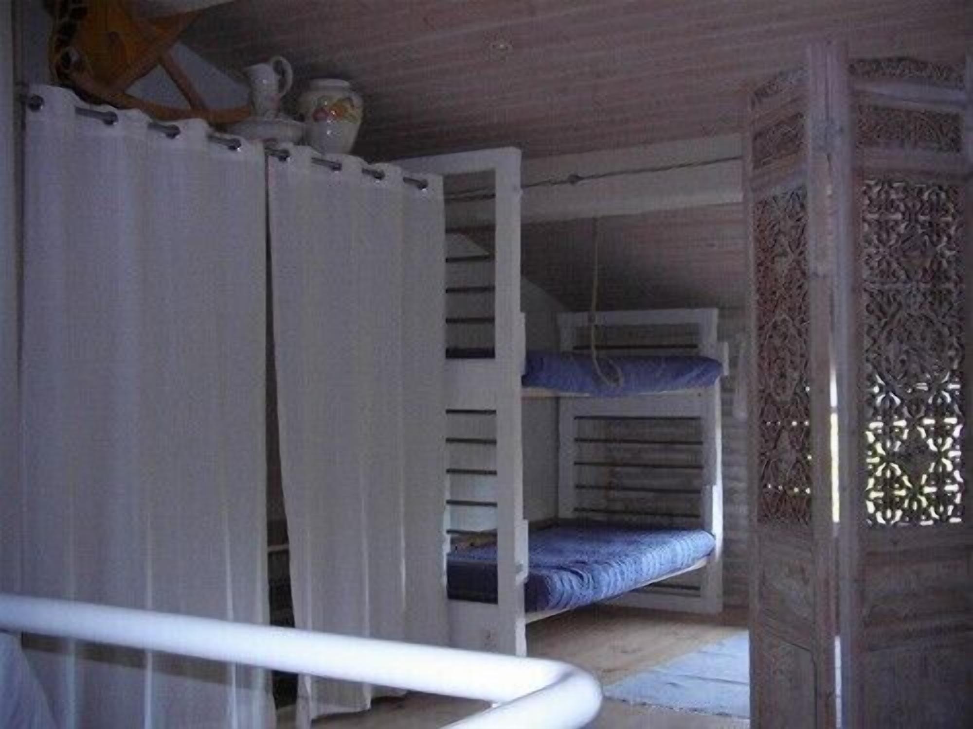 Een kamer met een stapelbed, een gordijn en een decoratief houten paneel.