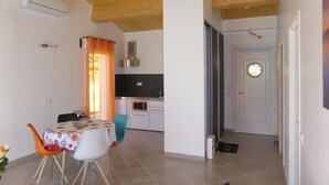 A modern kitchen with white cabinets and a black countertop. There is a dining area with a table and chairs, and a wooden ceiling. - Lodging 4 Gîte RE CLIMATISE IN THE CALM OF THE GREAT VERSENNES  (Saintes)
