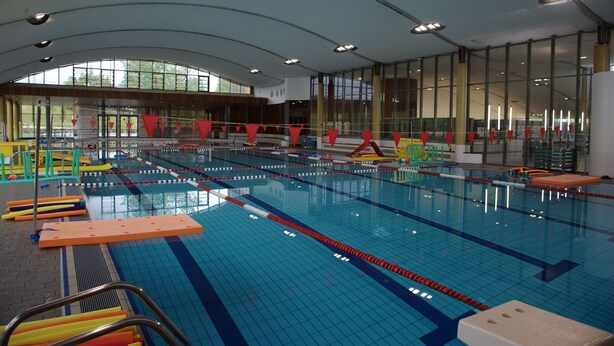 An indoor swimming pool with multiple lanes, safety equipment, and a high ceiling with large windows. - Lodging 4 Gîte RE CLIMATISE IN THE CALM OF THE GREAT VERSENNES  (Saintes)