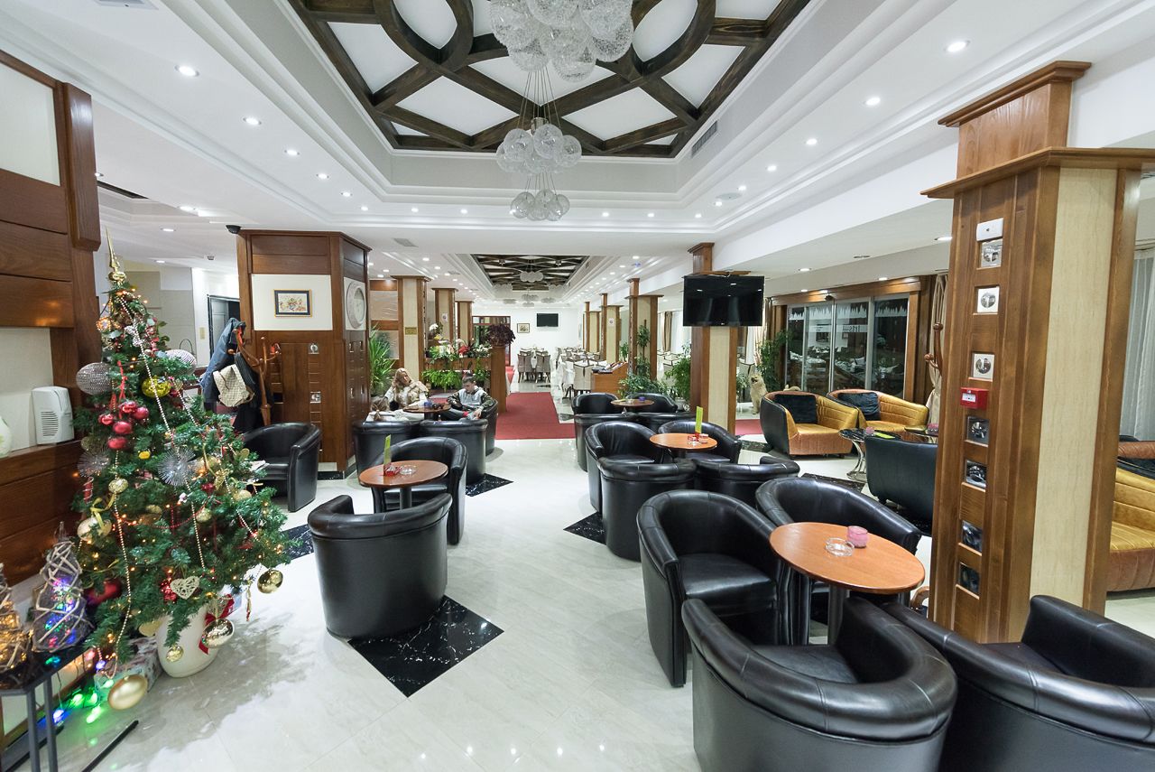 Un hall d’hôtel décoré d’un sapin de Noël, doté de fauteuils en cuir et d’un grand lustre.