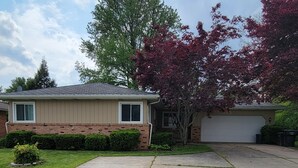 A two-story house with a garage, a well-maintained lawn, and a tree with red leaves. - Updated clean 5br house, 2(1/2) bath close to Notre Dame. (South Bend)